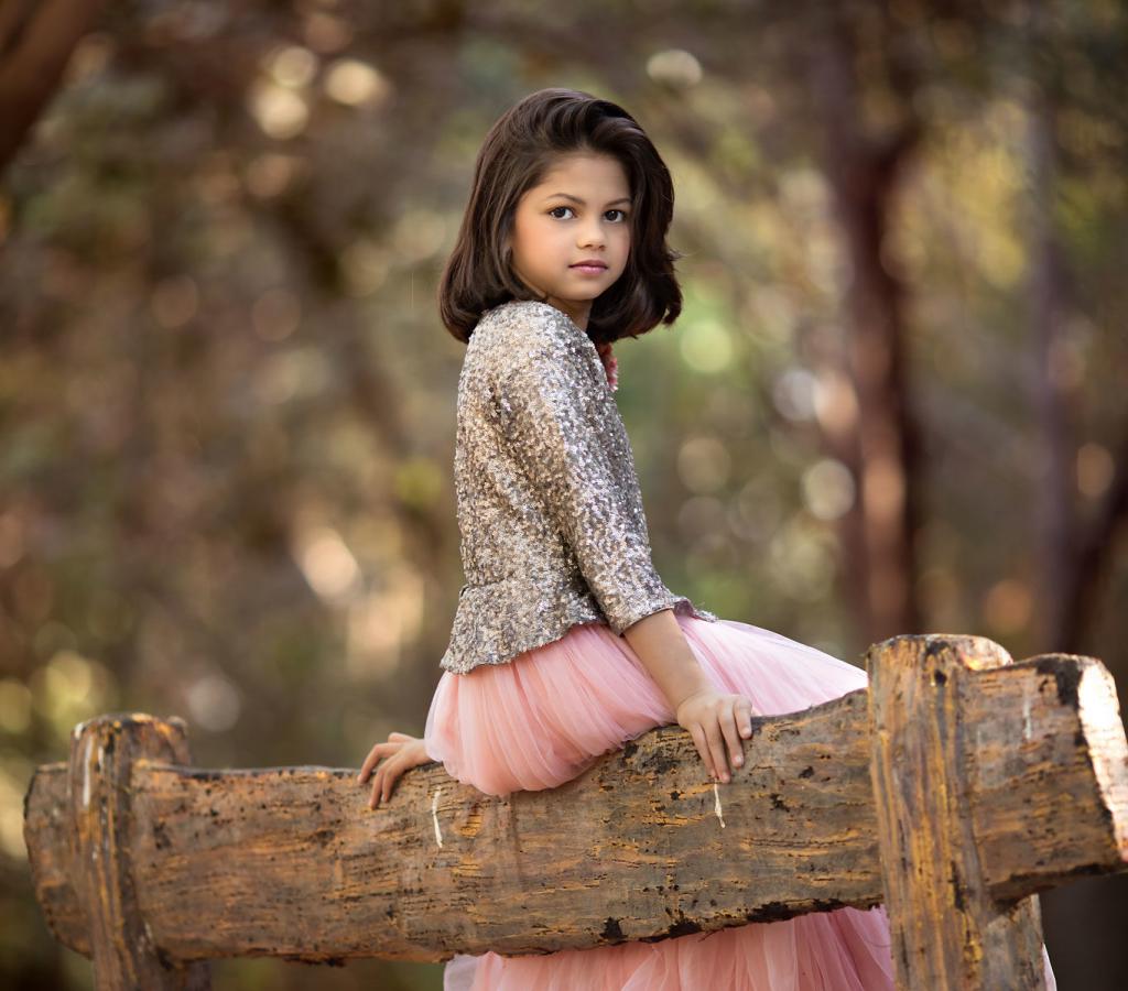 Маленькая девочка сидит на бревне