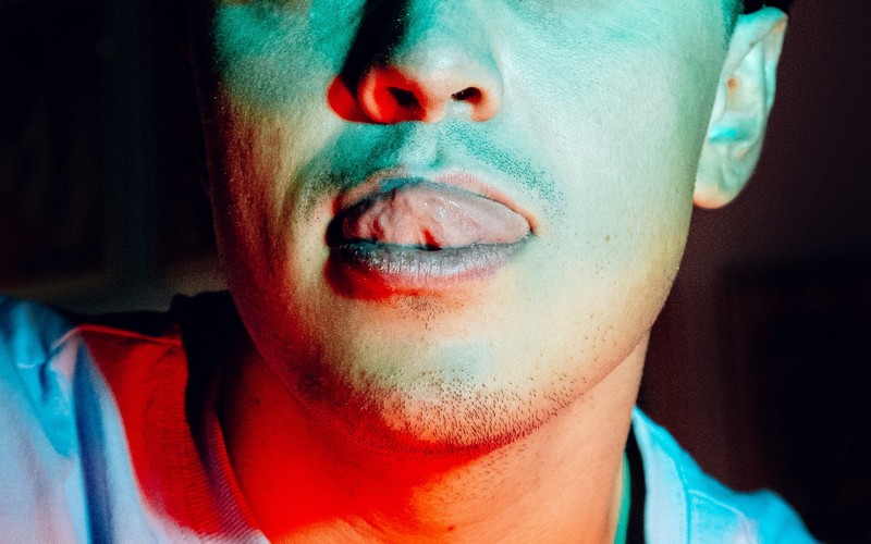 Мужчина прикасается языком к верхней губе