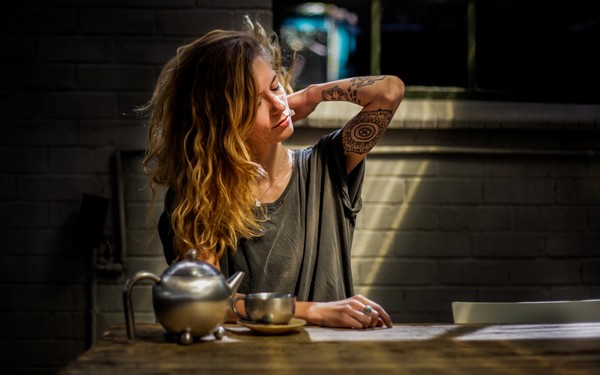 Девушка сидит за столом и чешет шею сзади