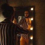 Мужчина в очках напротив зеркала