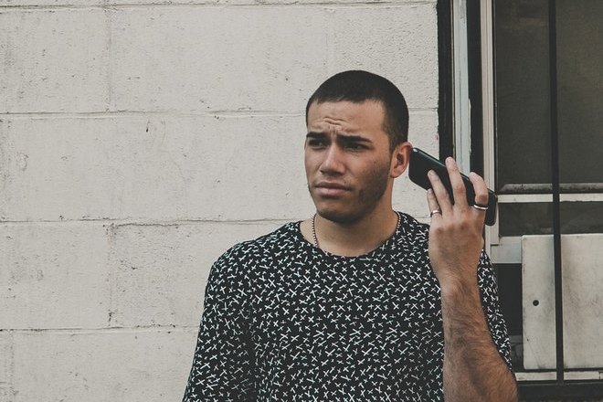 Парень чешет ухо телефоном