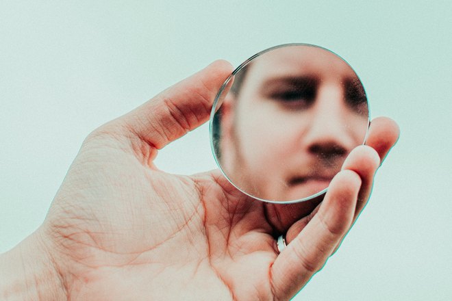 Мужчина отражается в маленьком круглом зеркале