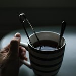 Чашка чая с ложкой в левой руке