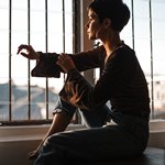 Женщина сидит на столе возле окна