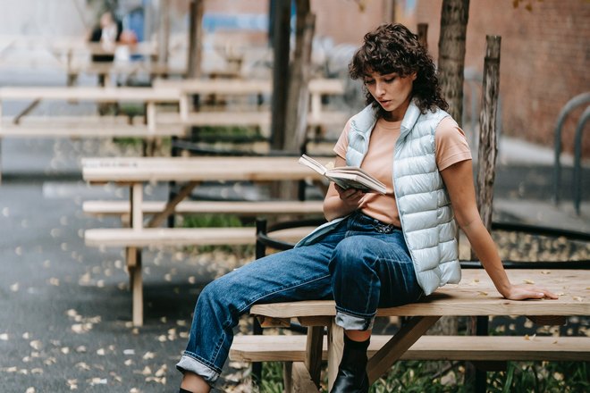 Девушка сидит на столе и читает