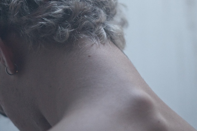 Мужчина с серьгой и родинкой на шее