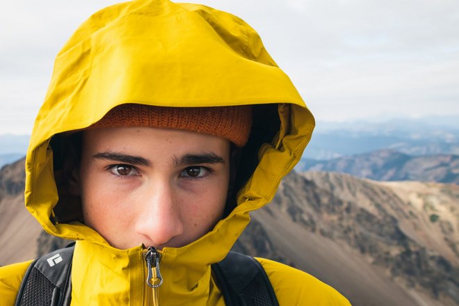 Парень в желтой куртке на фоне гор