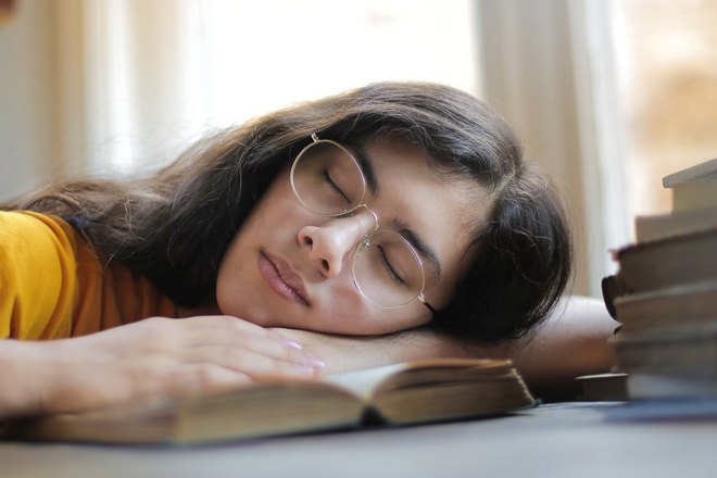 Девушка в очках спит на книге