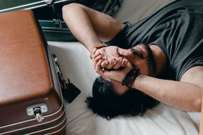 Бородатый мужчина спит возле чемодана