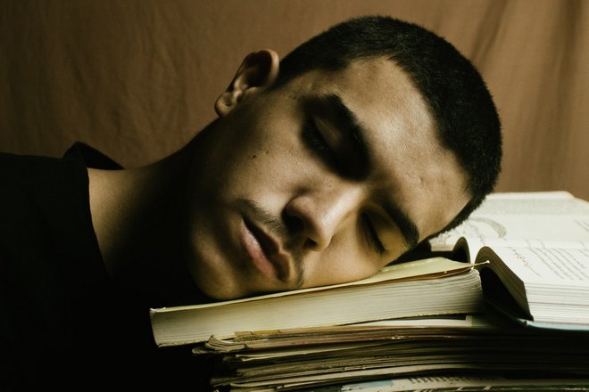 парень спит над учебниками