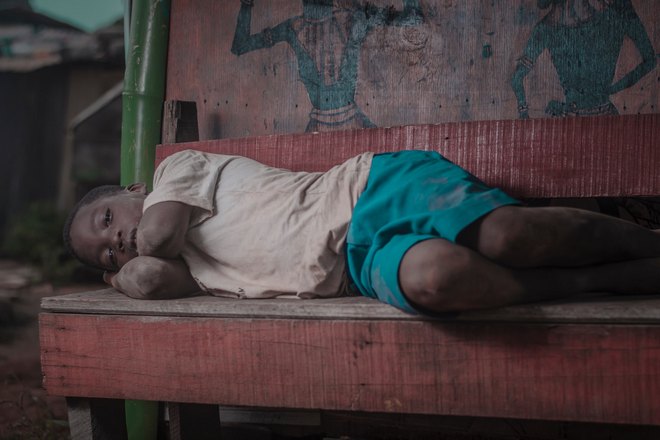 темнокожий мальчик спит на лавке