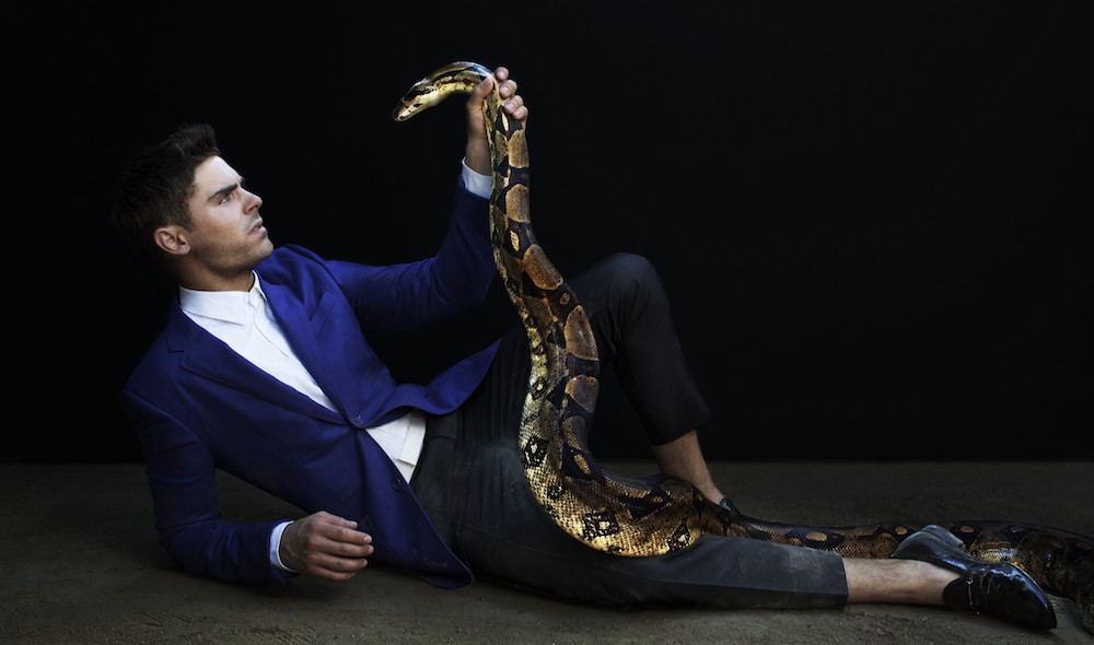 мужчина в синем пиджаке держит змею