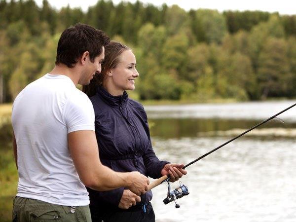 Мужчина учит женщину ловить рыбу